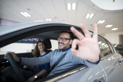 Happy customer buying new car at dealership.